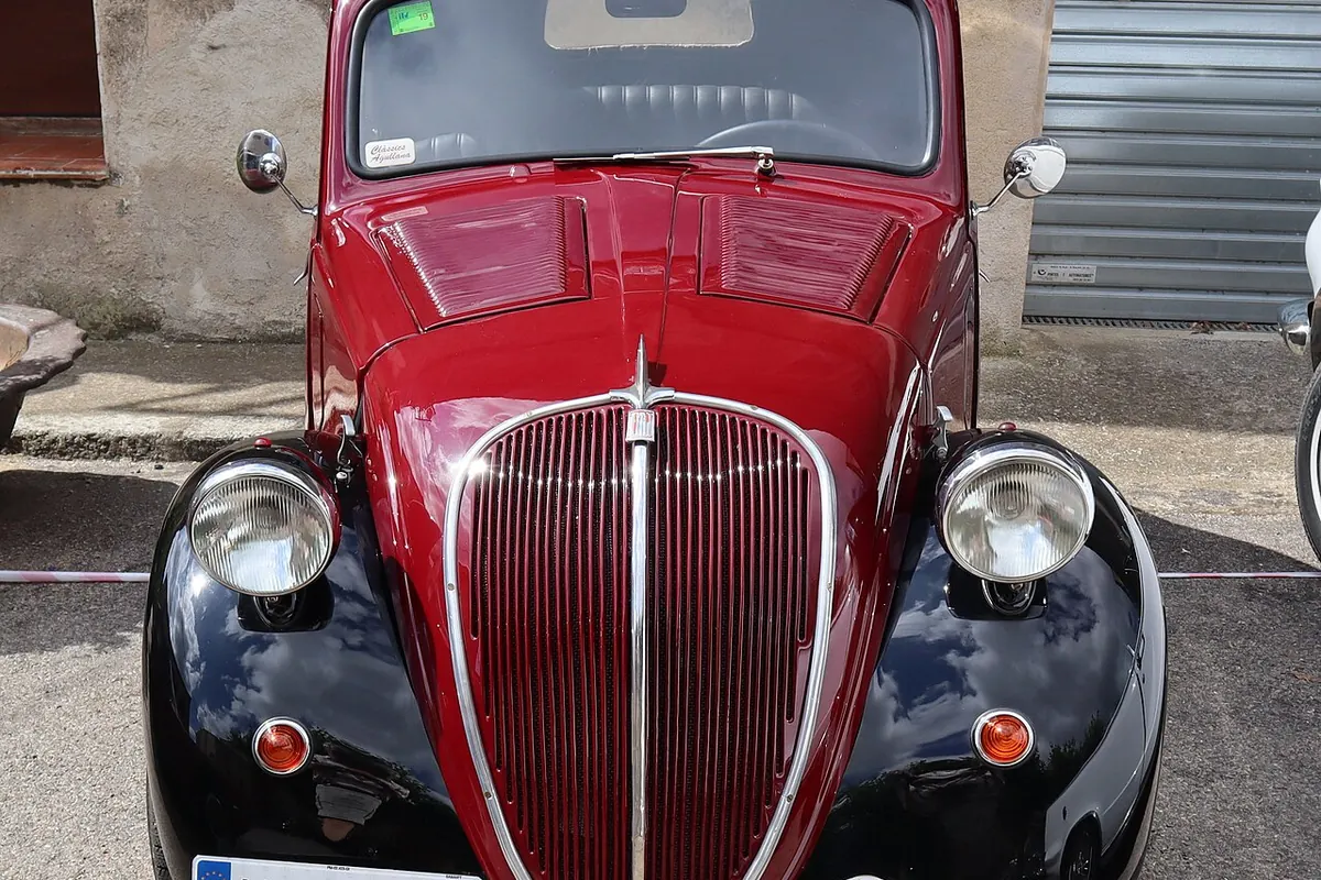 Бордо-черен Fiat 500 „Тополино“ от 1948 г., заснет отпред: двата кръгли фара приличат на очи, а хромираната решетка – на дълъг нос